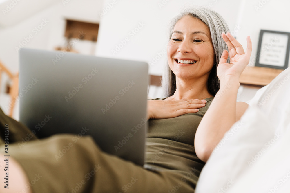 Mature asian woman gesturing and working with laptop Mature asian woman gesturing and working with laptop