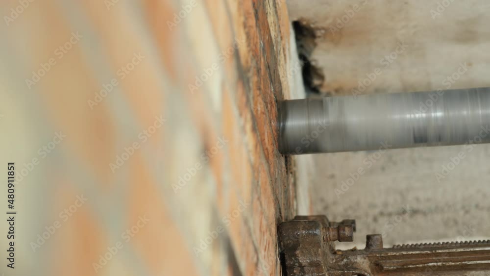 Builder drills a hole in the brick wall with a powerful power tool