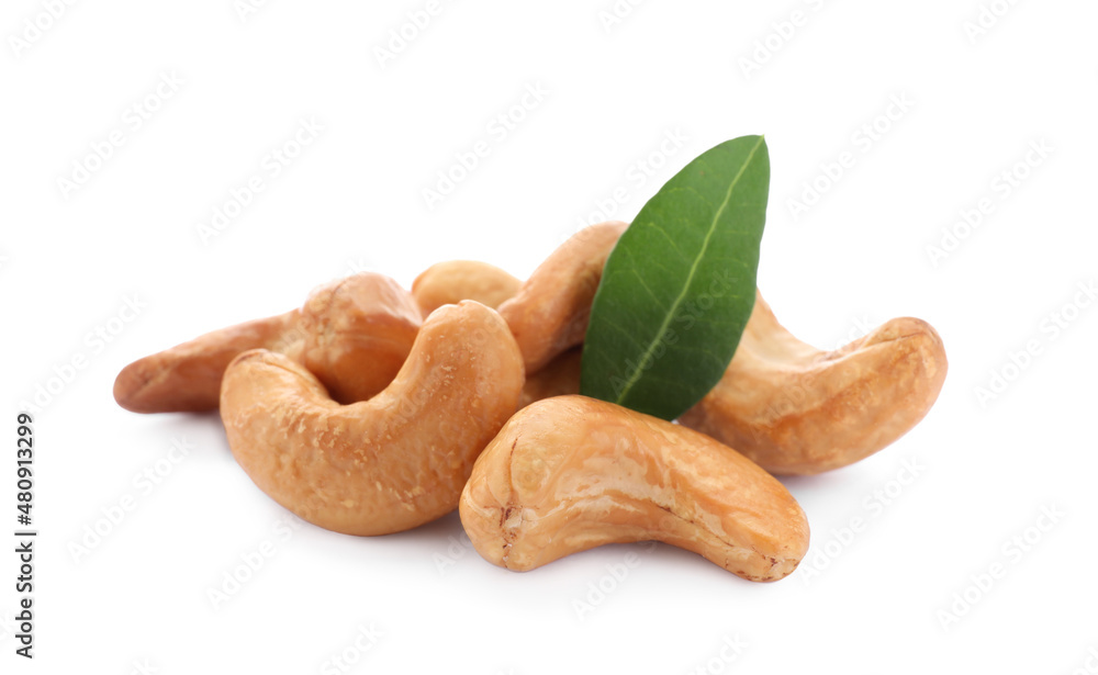Fototapeta premium Pile of tasty organic cashew nuts and green leaf isolated on white