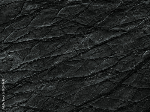 Black rock texture with cracks and veins. Close-up. Dark rough stone surface background for design.