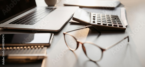 Accountant workplace, calculator, laptop computer and glasses at office desk panoramic banner, finance, business and accounting concept photo