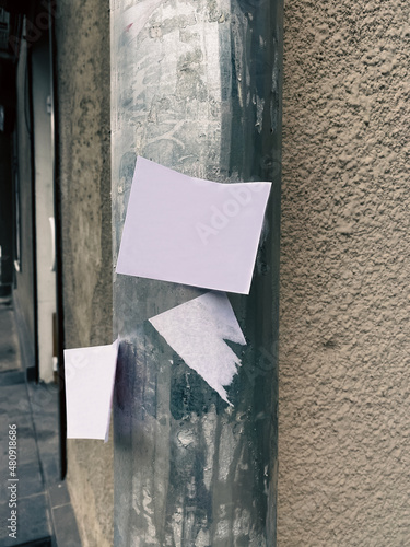 White paper sheet of advertisement on a pole against the background of the Street Wall - outdoor advertising on paper sheets. Pasting of outdoor advertising ads. Postcard and bill posting concept.  photo