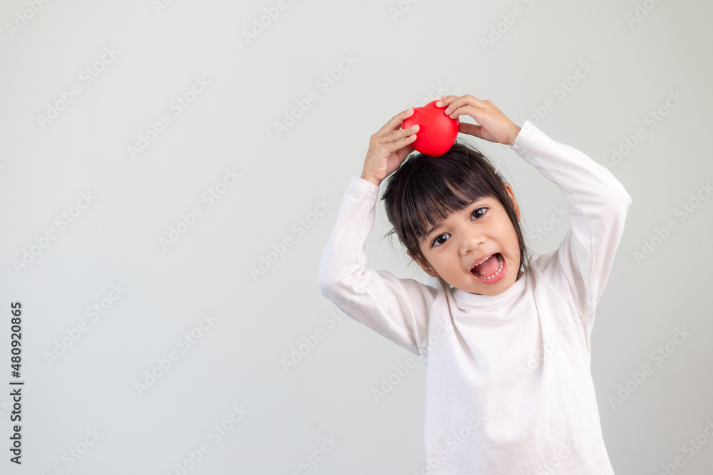 The little girl in a white shirt holding a red heart on a white background. Greeting cards for valentine's day, mother's day, father's day. The little girl in a white shirt holding a red heart on a white background. Greeting cards for valentine's day, mother's day, father's day.