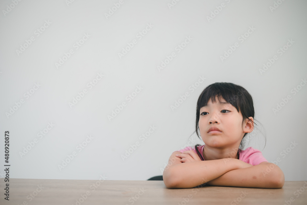 asian child rest her cheeks on the fists with moody face asian child rest her cheeks on the fists with moody face