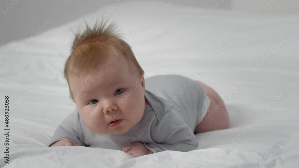 Adorable Newborn Redhead Baby Lying On Tummy While Relaxing On Bed At Home Adorable Newborn Redhead Baby Lying On Tummy While Relaxing On Bed At Home