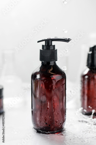 A mockup of a cosmetic moisturizer in a splash of water. A brown bottle with a gel dispenser. 