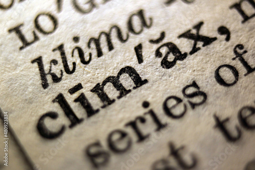 Word "climax" and "violent" printed on book page, macro close-up 