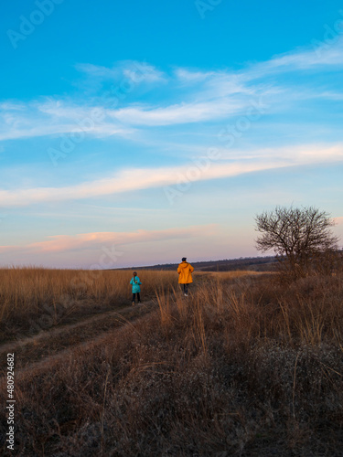 Travelers father and daughter walking together on hill enjoying scenic landscape blue cloudy sunset sky back view. Active Lifestyle nature tourism. Family local travel hiking trail journey Backpacking