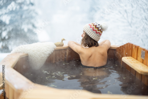Fototapeta Woman relaxing in hot bath outdoors, sitting back and enjoying beautiful view on snowy mountains
