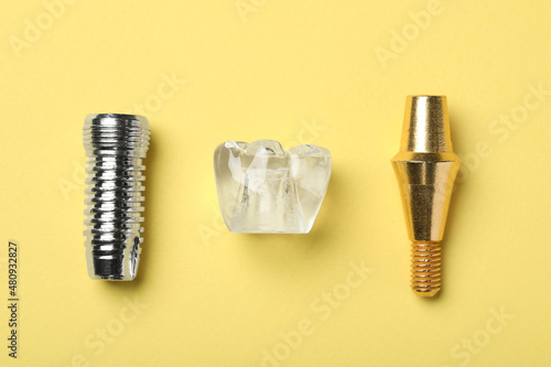 Parts of dental implant on yellow background, flat lay
