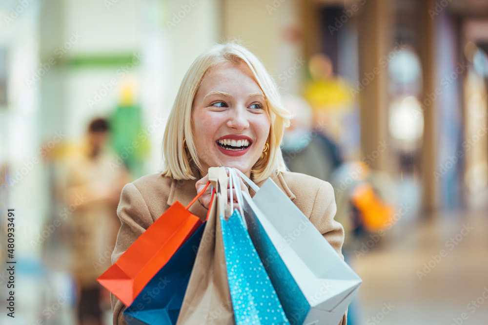 Crazy fashion girl doing shopping in mall center - Happy blond woman having fun buying new clothes - Consumerism, people and youth lifestyle concept. Crazy fashion girl doing shopping in mall center - Happy blond woman having fun buying new clothes - Consumerism, people and youth lifestyle concept.