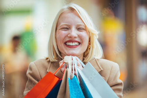 Excited woman having fun shopping and holding bags while looking at the camera smiling. Beautiful woman holding shopping bags and smiling. Young beautiful girl is shopping in the Mall
