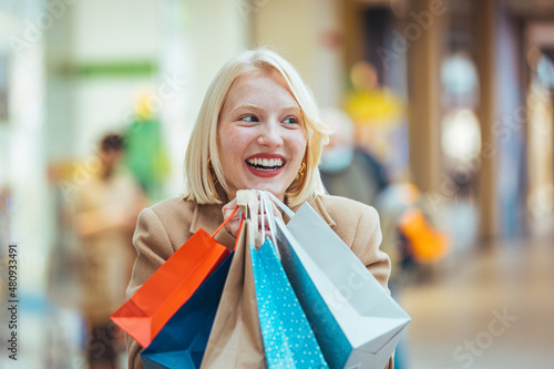 Crazy fashion girl doing shopping in mall center - Happy blond woman having fun buying new clothes - Consumerism, people and youth lifestyle concept.