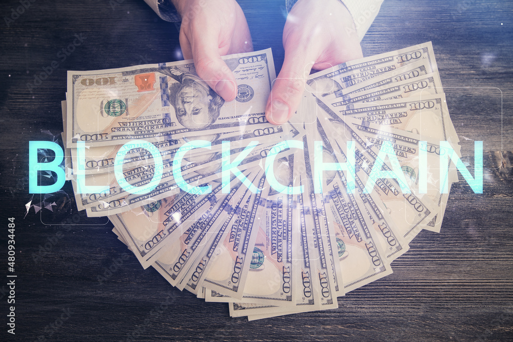 Multi exposure of blockchain theme drawing hologram and USA dollars bills and man hands. Business concept. Multi exposure of blockchain theme drawing hologram and USA dollars bills and man hands. Business concept.