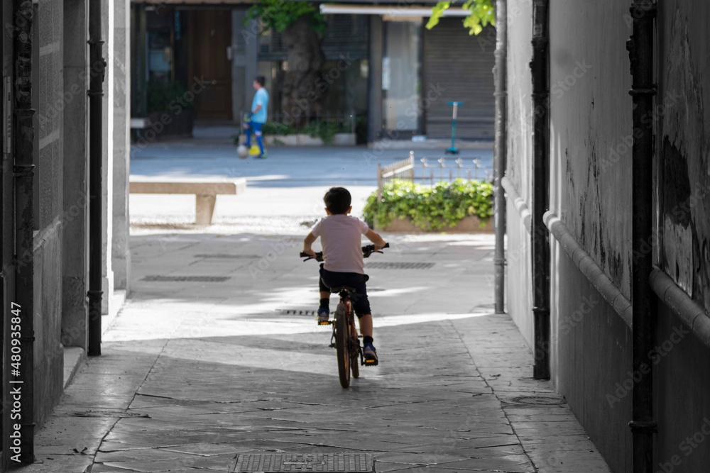 Niño en bicicleta en calle estrecha hacia parque