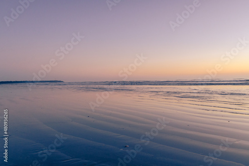 beach at sunset with linear formations in the sand with water with orange colors