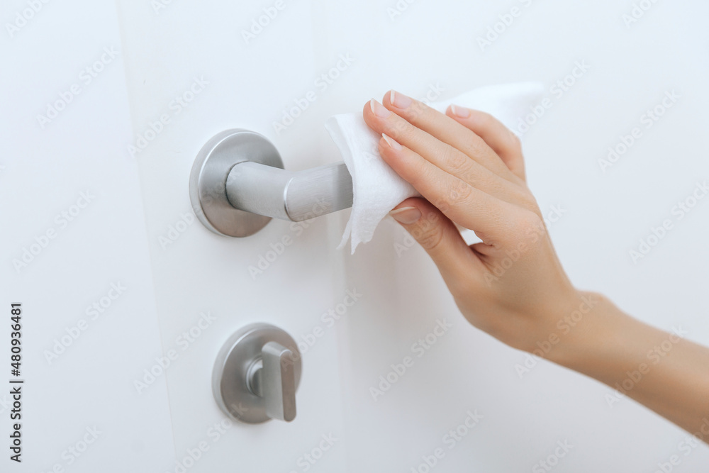 Cleaning door handles with an antiseptic wet wipe and gloves. Sanitize surfaces prevention in hospital and public spaces against corona virus. Woman hand using towel for cleaning home room door link Cleaning door handles with an antiseptic wet wipe and gloves. Sanitize surfaces prevention in hospital and public spaces against corona virus. Woman hand using towel for cleaning home room door link