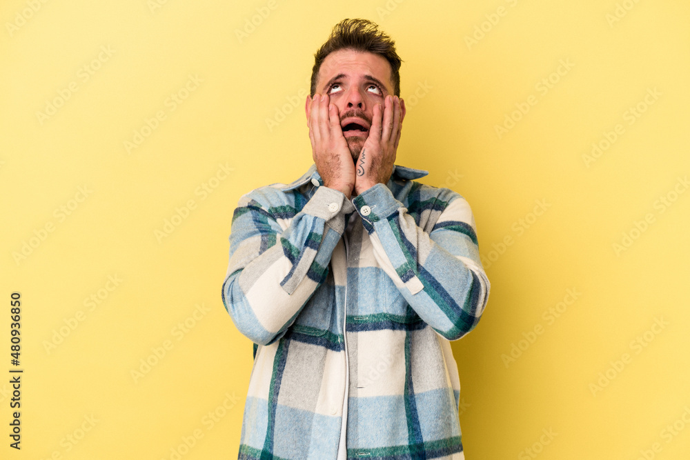 Young caucasian man isolated on yellow background whining and crying disconsolately. Young caucasian man isolated on yellow background whining and crying disconsolately.