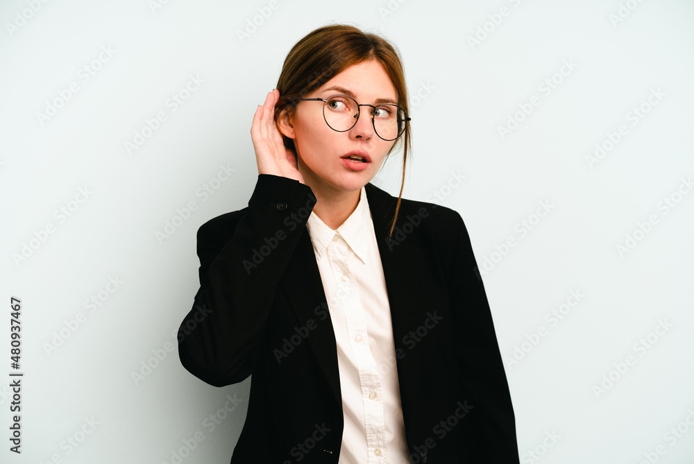 Young business English woman isolated on blue background trying to listening a gossip. Young business English woman isolated on blue background trying to listening a gossip.
