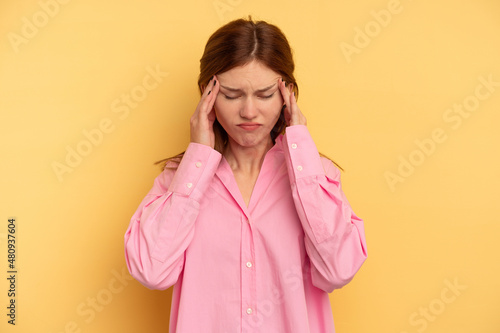 Young English woman isolated on yellow background touching temples and having headache. © Asier