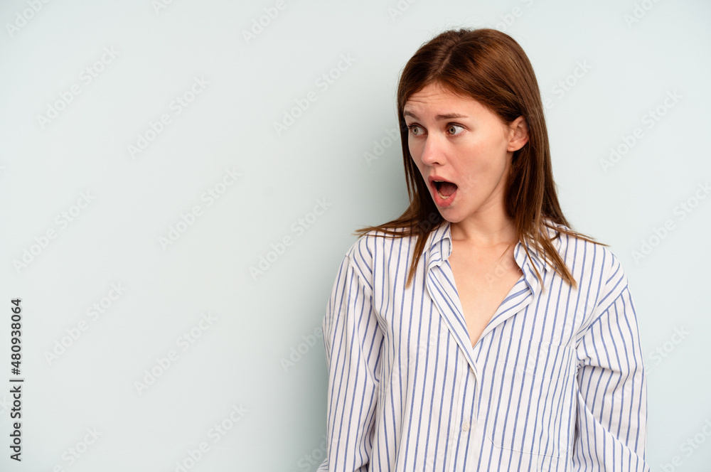 Young English woman isolated on blue background being shocked because of something she has seen. Young English woman isolated on blue background being shocked because of something she has seen.