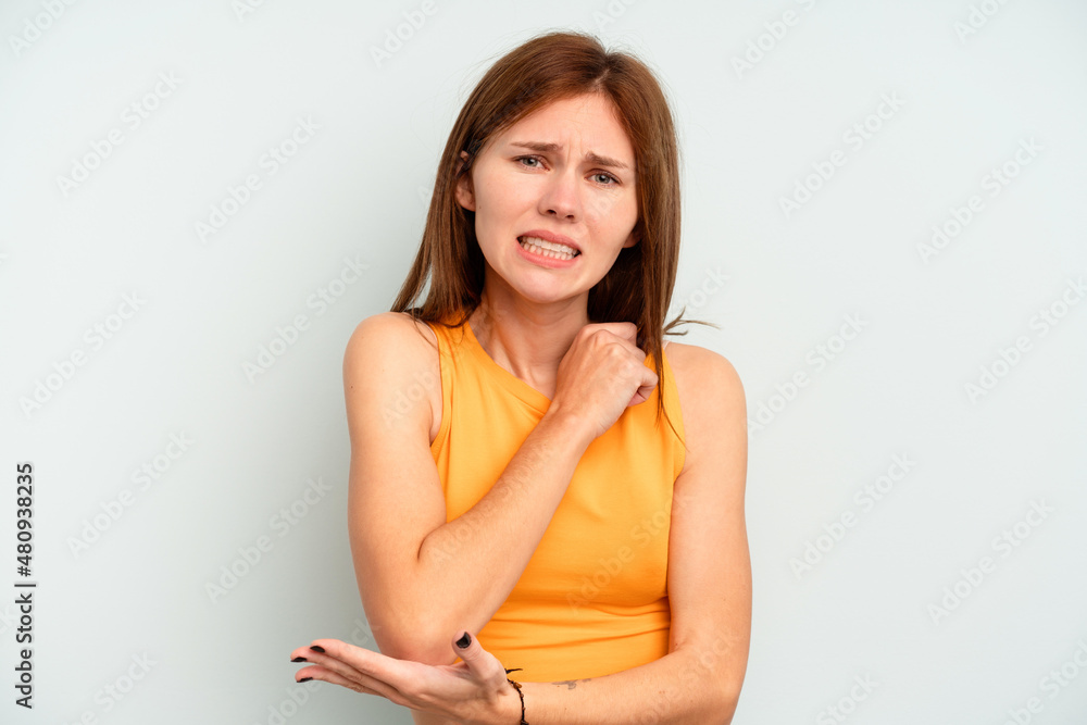 Young English woman isolated on blue background massaging elbow, suffering after a bad movement. Young English woman isolated on blue background massaging elbow, suffering after a bad movement.