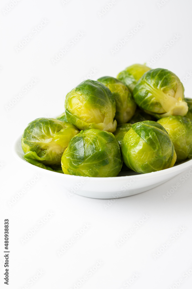 Close-up of green Brussels sprouts on white plate, white background, vertical, with copy space Close-up of green Brussels sprouts on white plate, white background, vertical, with copy space