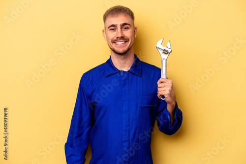 Young electrician caucasian man isolated on yellow background happy, smiling and cheerful.