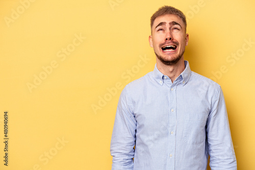 Young caucasian man isolated on yellow background shouting very angry, rage concept, frustrated.