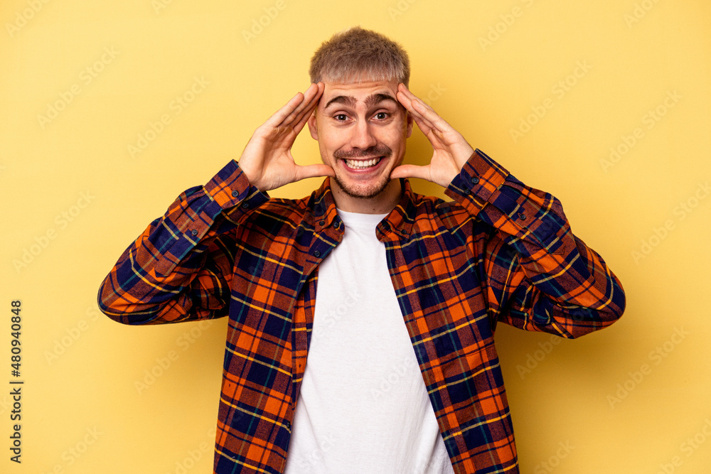 Young caucasian man isolated on yellow background receiving a pleasant surprise, excited and raising hands. Young caucasian man isolated on yellow background receiving a pleasant surprise, excited and raising hands.