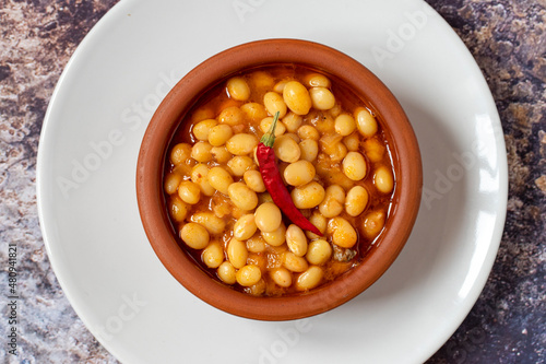 Hot turkish bean stew on wooden background. Ispir beans cooked in a casserole - Kuru Fasulye. Top view