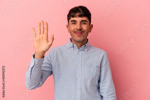 Young mixed race man isolated on pink background smiling cheerful showing number five with fingers.