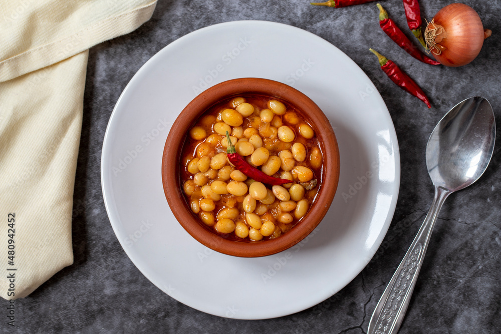 Hot turkish bean stew on dark background. Ispir beans cooked in a casserole - Kuru Fasulye. Top view Hot turkish bean stew on dark background. Ispir beans cooked in a casserole - Kuru Fasulye. Top view