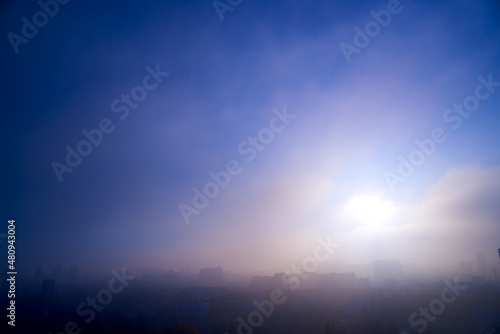Foggy cityscape at sunset time.
