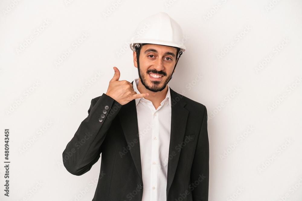 Young architect man wearing a construction helmet isolated on white background showing a mobile phone call gesture with fingers. Young architect man wearing a construction helmet isolated on white background showing a mobile phone call gesture with fingers.