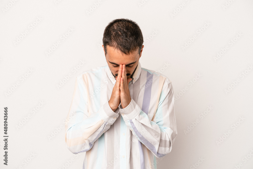 Young caucasian man isolated on white background praying, showing devotion, religious person looking for divine inspiration. Young caucasian man isolated on white background praying, showing devotion, religious person looking for divine inspiration.