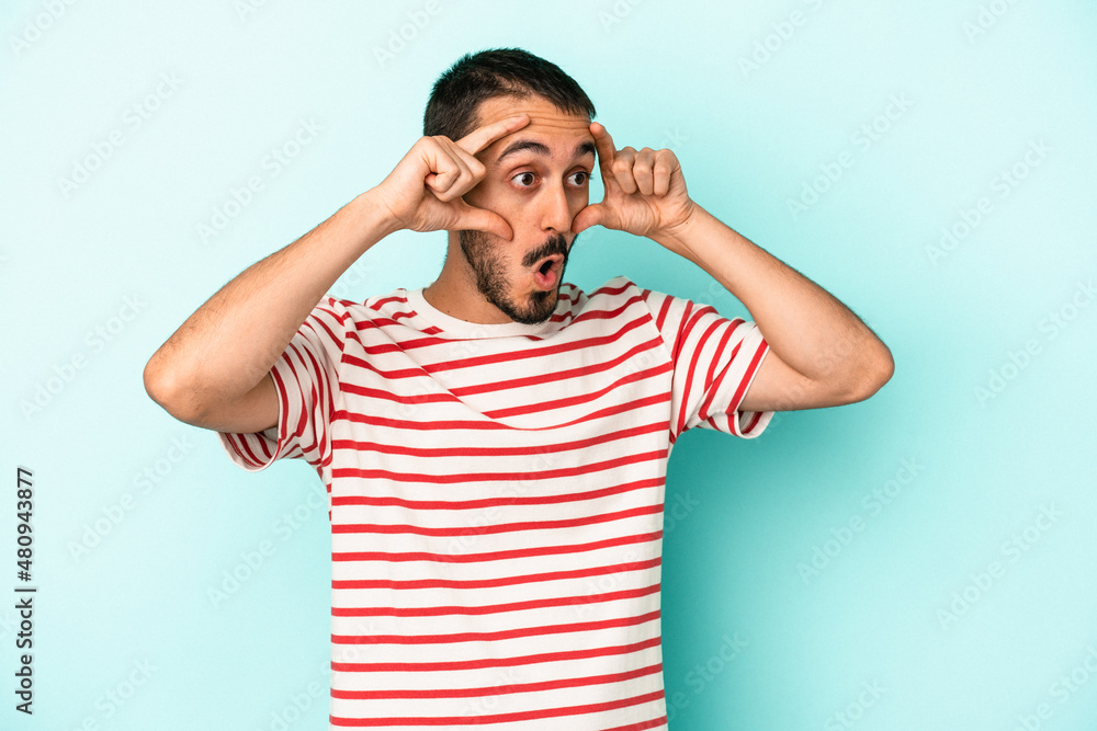 Young caucasian man isolated on blue background keeping eyes opened to find a success opportunity. Young caucasian man isolated on blue background keeping eyes opened to find a success opportunity.