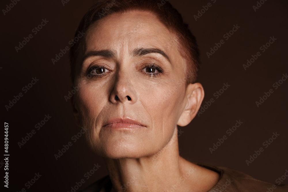 Obraz premium Senior ginger woman with short hair posing and looking at camera