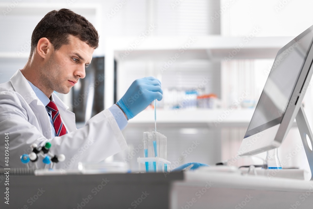 Viorolog researcher examining a sample from test tube working in a modern equipped laboratory. Viorolog researcher examining a sample from test tube working in a modern equipped laboratory.