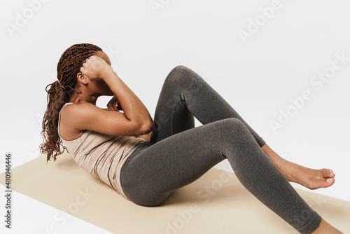 Young black woman doing exercise while working out on mat