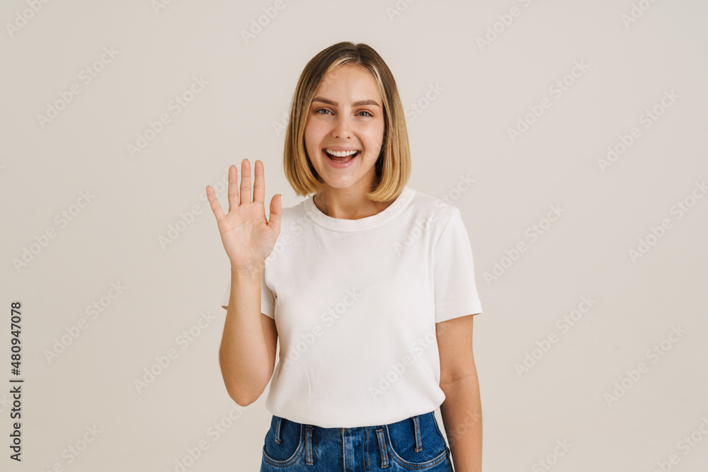 Young blonde woman smiling while waving hand at camera Young blonde woman smiling while waving hand at camera