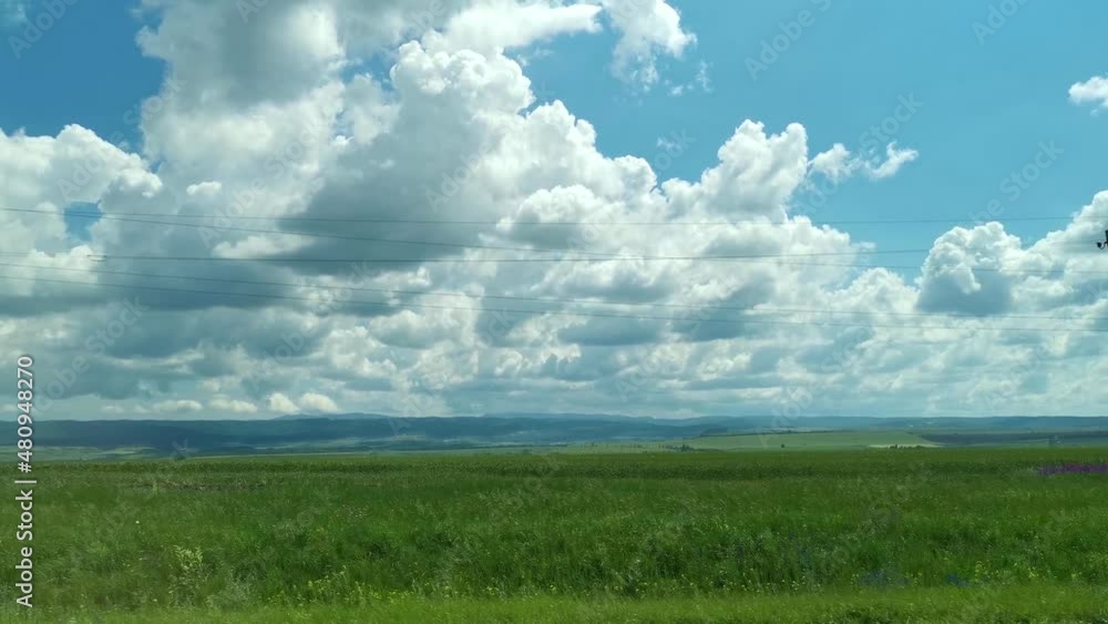 Green fields road car window. View from the side window of the green spring wheat fields and clouds floating across the blue sky. Travel on the roads of Russia, a breathtaking view from the car window Green fields road car window. View from the side window of the green spring wheat fields and clouds floating across the blue sky. Travel on the roads of Russia, a breathtaking view from the car window