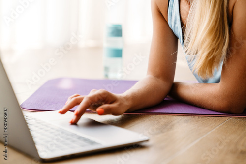 Blonde woman using laptop during yoga practice at home
