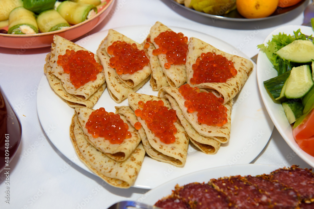 Red caviar on pancakes. Russian traditional dish on a plate. Red caviar on pancakes. Russian traditional dish on a plate.