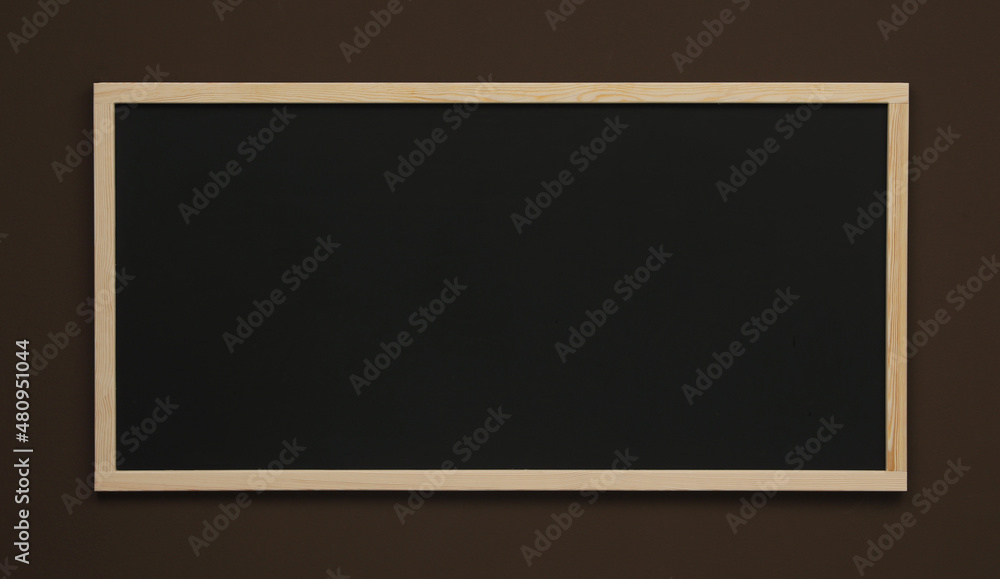 Clean black chalkboard hanging on brown wall Clean black chalkboard hanging on brown wall