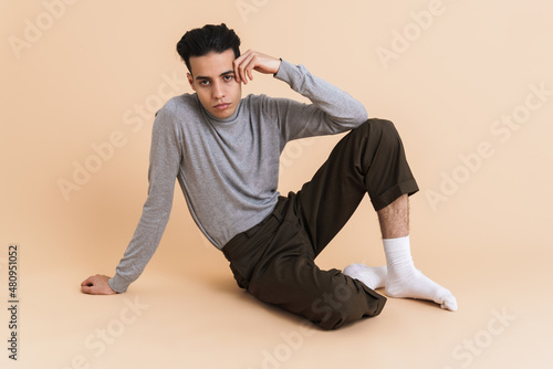 Young middle eastern man looking at camera while sitting on floor