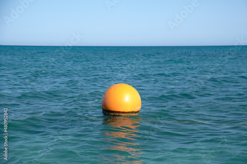 Orange buoy floating on sea surface waves. Human life safety concept © bilanol