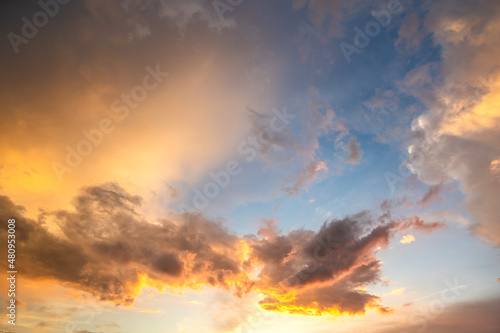 Dramatic sunset sky landscape with puffy clouds lit by orange setting sun and blue heavens © bilanol