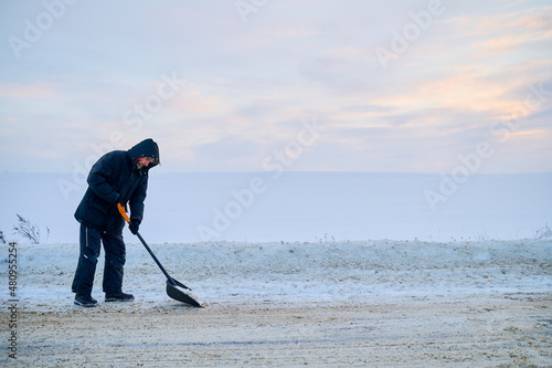 A man cleans snow against the background of an endless snow field