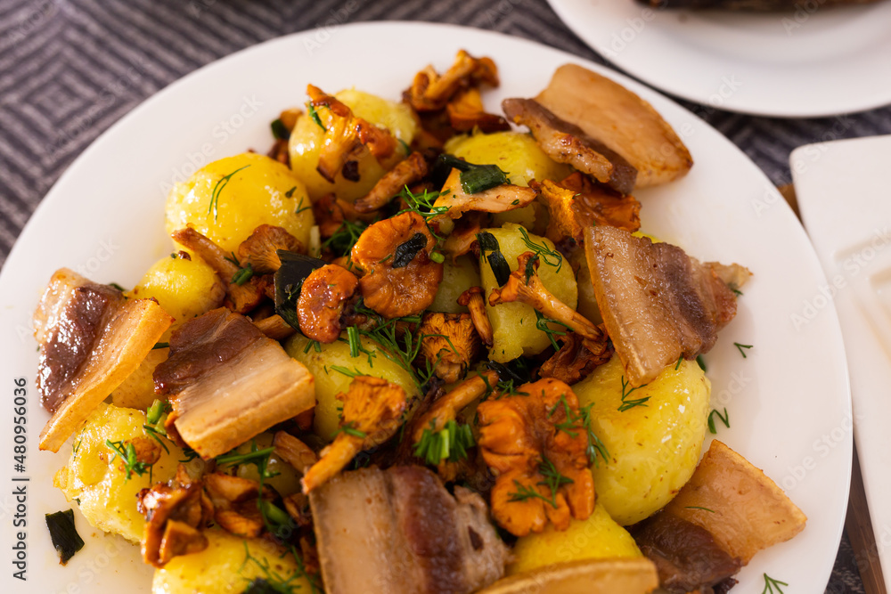 traditional rustic dish. fried potatoes with chanterelle mushrooms and pork brisket with herbs traditional rustic dish. fried potatoes with chanterelle mushrooms and pork brisket with herbs